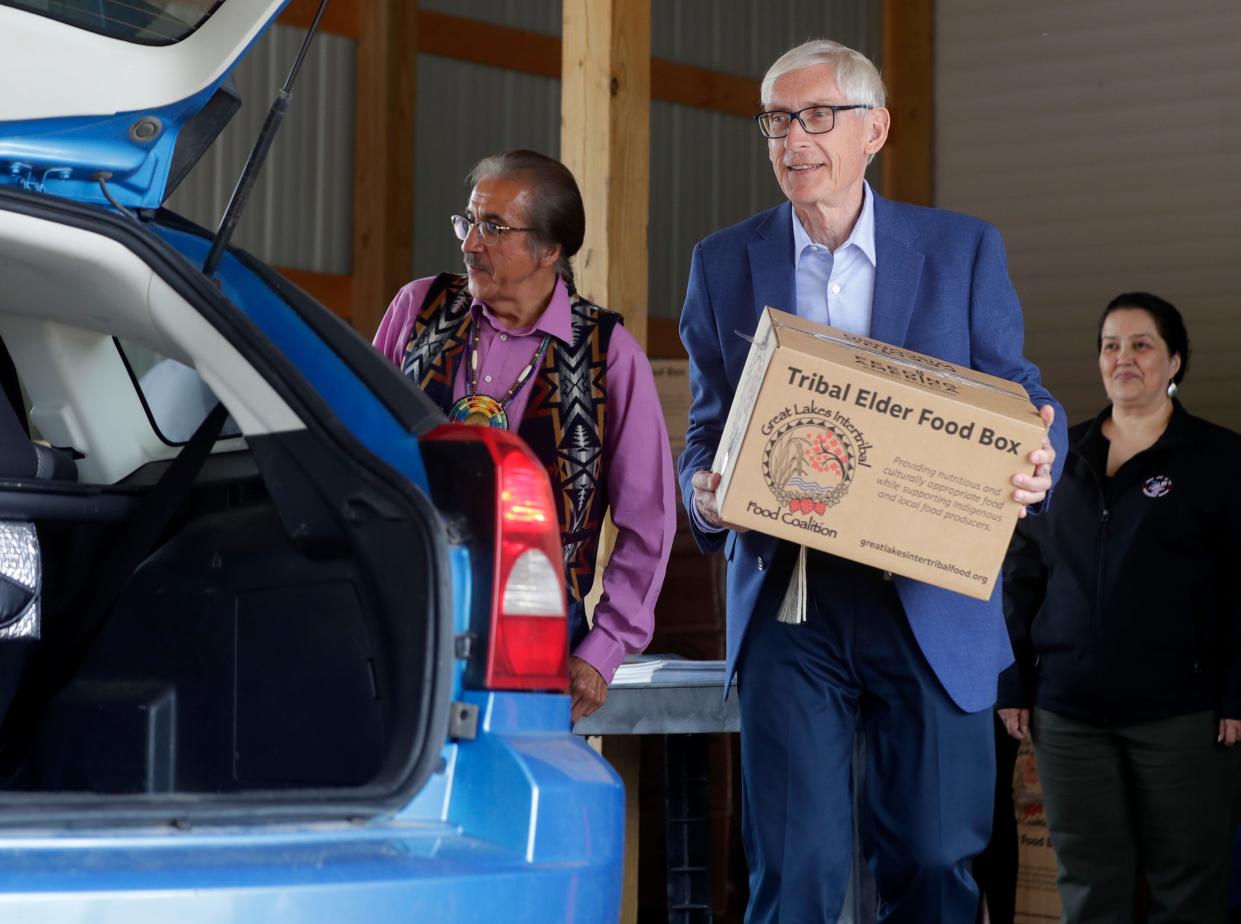 Gov. Tony Evers helps load tribal elder food boxes into vehicles while visiting the Menominee Nation Food Distribution on June 15, 2023, in Keshena, Wis.