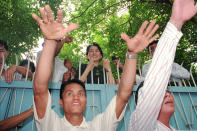 FILE - A guard signals to crowds that gathered outside Aung San Suu Kyi's Rangoon home, to sit down as she is about to address a large number of Burmese supporters from above the gate on July 15, 1995. Suu Kyi is the daughter of the country’s independence hero, Gen. Aung San, who was assassinated in 1947, less than six months before the country, then called Burma, became independent from Britain. Suu Kyi moved to New Delhi in 1960 when her mother was appointed ambassador to India and then spent most of her young adult life in the United States and England. Her career in politics began in 1988. (AP Photo/Anat Givon, File)