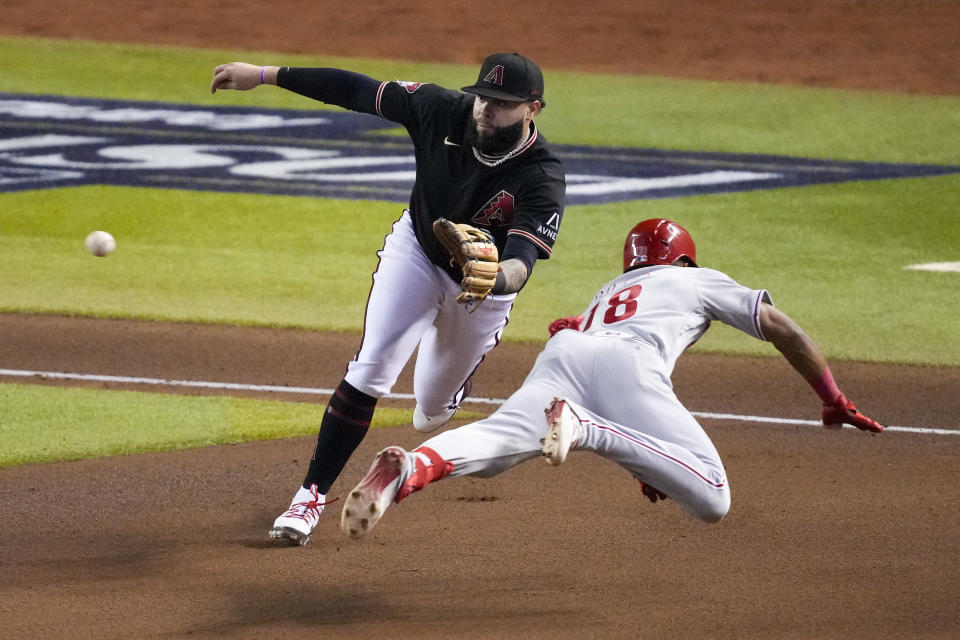 Philadelphia Phillies' Johan Rojas is safe past Arizona Diamondbacks third baseman Emmanuel Rivera after a triple during the seventh inning in Game 4 of the baseball NL Championship Series in Phoenix, Friday, Oct. 20, 2023. (AP Photo/Rick Scuteri)