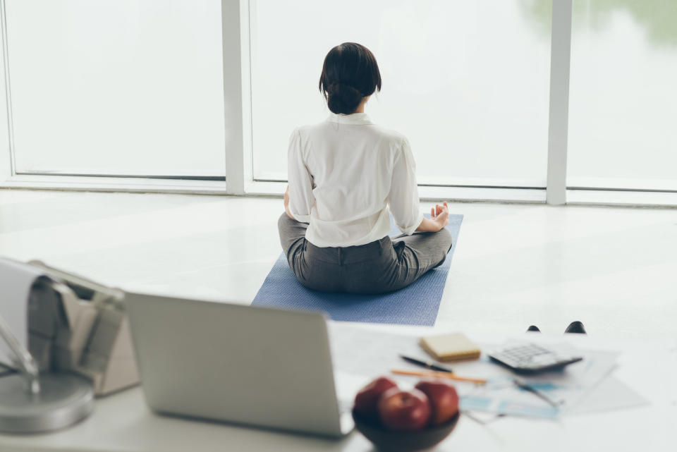 Office worker meditating on the floor, rear view