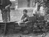 West Berlin children, from left, Peter Friedrich, 5, Katrin Kuhl, 4, and Jurgen Bottcher, 8, build a pretend Berlin Wall in a vacant lot in October 1961. (Paul Schutzer—Time & Life Pictures/Getty Images) <br> <br> <a href="http://life.time.com/history/berlin-wall-photos-early-days-of-the-cold-war/#1" rel="nofollow noopener" target="_blank" data-ylk="slk:Click here to see the full collection at LIFE.com;elm:context_link;itc:0;sec:content-canvas" class="link ">Click here to see the full collection at LIFE.com</a>