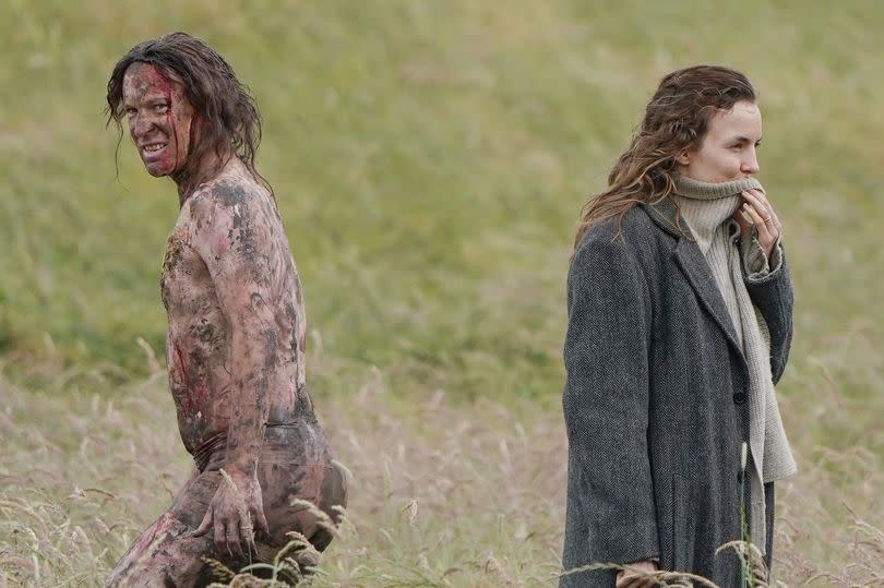 Jodie Comer laughing alongside a cast member playing a zombie