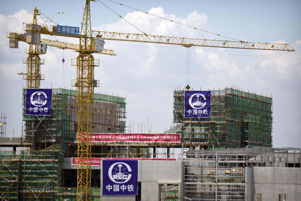 In this Nov. 14, 2018, photo, cranes rise above a building with banners in Chinese and English and being built by Chinese state-owned construction firm China Railway Group Limited in Port Moresby, Papua New Guinea. As world leaders arrive in Papua New Guinea for a Pacific Rim summit, the welcome mat is especially big for China’s President Xi Jinping. With both actions and words, Xi has a compelling message for the South Pacific’s fragile island states, long both propped up and pushed around by U.S. ally Australia: they now have a choice of benefactors. (AP Photo/Mark Schiefelbein)