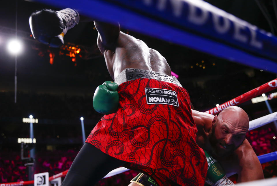 Deontay Wilder, left, knocks down Tyson Fury, of England, in a heavyweight championship boxing match Saturday, Oct. 9, 2021, in Las Vegas. (AP Photo/Chase Stevens)