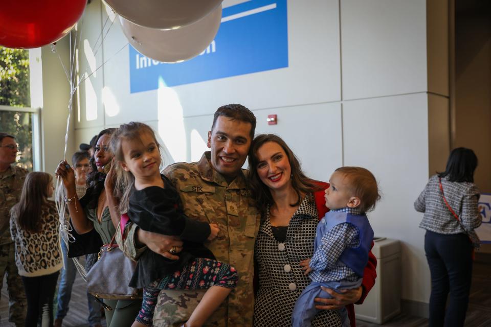 Alabama National Guard Major Joshua Sik stands with his wife and two young children at the welcome home ceremony for the 135th Expeditionary Sustainment Command in Birmingham, Ala., January 14, 2023.