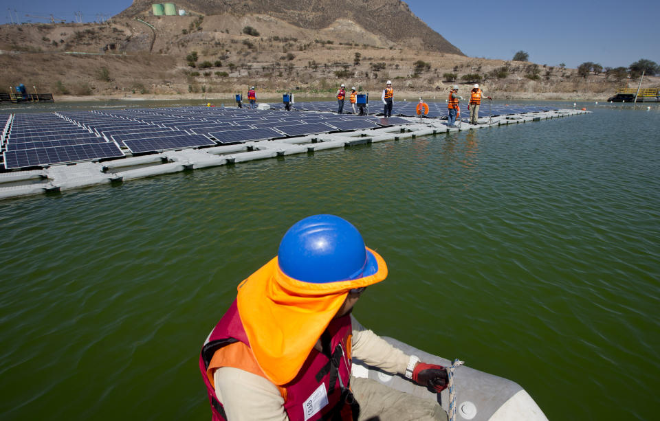 A worker on a boat approaches a floating island of solar panels at Los Bronces mine, about 65 kilometers (approximately 40 miles) from Santiago, Chile, Thursday, March 14, 2019. Los Bronces is about 3,500 meters (11,500 feet) above sea level. In 2018, the mine produced 370,000 tons of fine copper and 2,421 tons of molybdenum. (AP Photo / Esteban Felix)