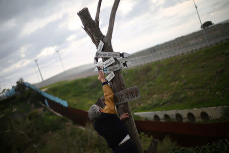 Mexican architect Carlos Torres, 68, adjusts signs near the double border fences separating Mexico and the United States, in Tijuana, Mexico. REUTERS/Edgard Garrido
