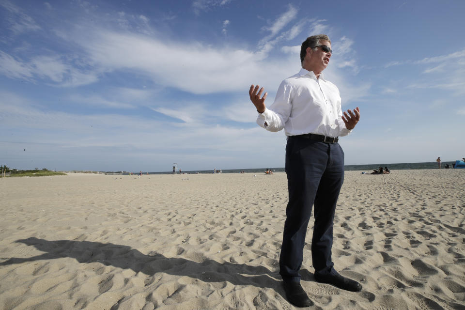 In this Aug. 21, 2019 photo, Andrew Gottlieb, executive director of the Association to Preserve Cape Cod, stands on Covell Beach in Centerville, Mass. near where the Vineyard Winds' proposed buried energy cables would stretch from offshore wind turbines, through the ocean, under the sand and parking lot, to a landing point onshore. The cables would then extend to a grid connection point inland. But as Trump has made clear how much he hates wind turbines, all the offshore wind projects, including the nation's first utility-scale offshore wind project, an 84 turbine, $2.8 billion wind farm slated to rise 15 miles off Martha's Vineyard, have stalled. (AP Photo/Elise Amendola)