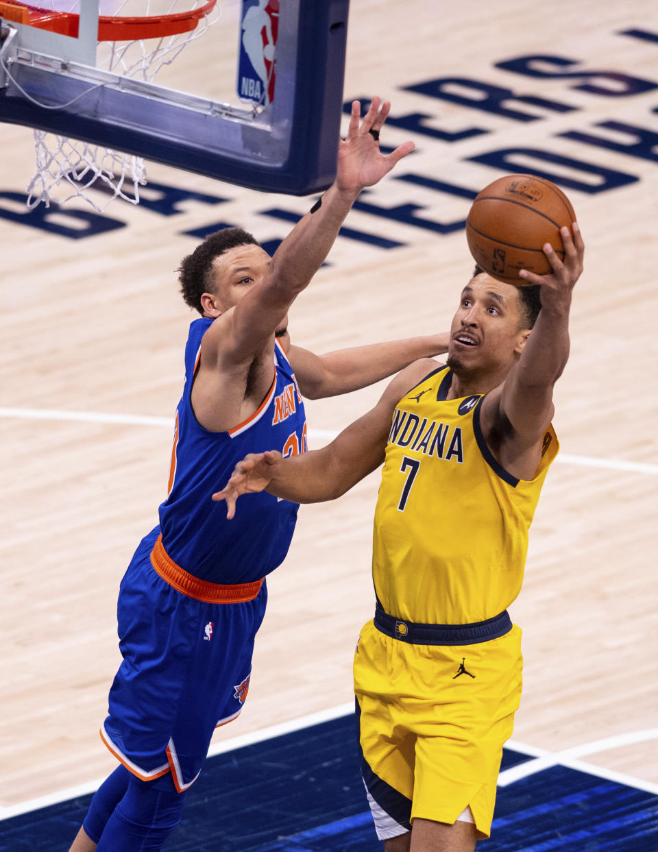 Indiana Pacers guard Malcolm Brogdon (7) makes a move around the defense of New York Knicks forward Kevin Knox II (20) during the first half of an NBA basketball game in Indianapolis, Saturday, Jan. 2, 2021. (AP Photo/Doug McSchooler)