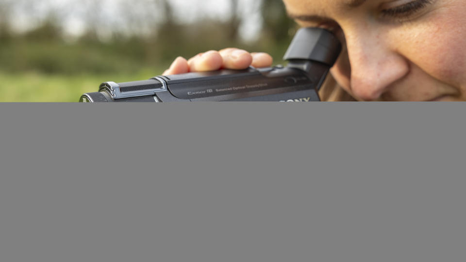 A close-up of a female photographer looking into the Sony FDR-AX53 viewfinder