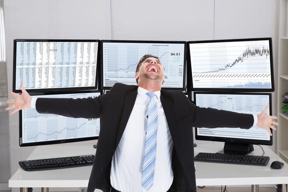 Elated investor in front of numerous computer screens