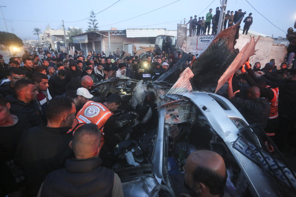 Palestinos rodean un auto alcanzado por un ataque aéreo israelí, el sábado 20 de enero de 2024, en Rafah, en la Franja de Gaza. (AP Foto/Hatem Ali)