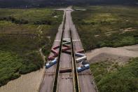 Containers block the Tienditas International Bridge, seen from Cucuta, Colombia, below, which connects with Tienditas, Venezuela, top, as the border has been partially closed for years by the Venezuelan government, Friday, Aug. 5, 2022. The border will gradually reopen after the two nations restore diplomatic ties when Colombia’s new president is sworn-in on Aug. 7, according to announcement in late July by Colombia’s incoming Foreign Minister Alvaro Leyva and Venezuelan Foreign Minister Carlos Faria. (AP Photo/Matias Delacroix)