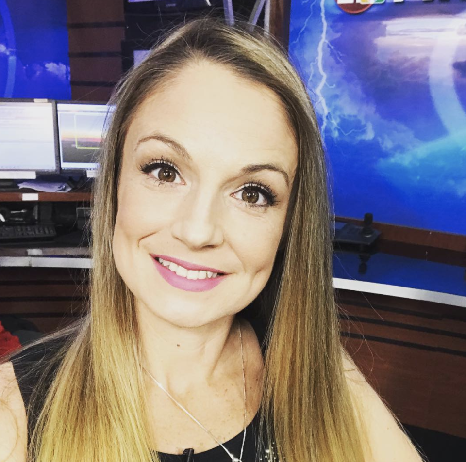 Kelly Plasker takes a selfie in front of screens in a TV studio.