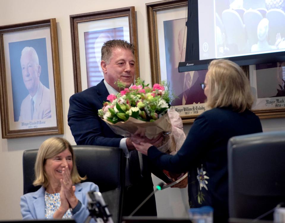 Newly elected Town Council President Bobbie Lindsay (left) smiles as town manager Kirk Blouin gives outgoing council president Maggie Zeidman flowers at Tuesday's town council meeting at Town Hall.