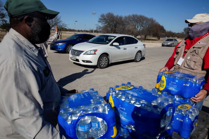 People collect water at a distribution site after winter weather caused electricity blackouts and water service disruption in Dallas