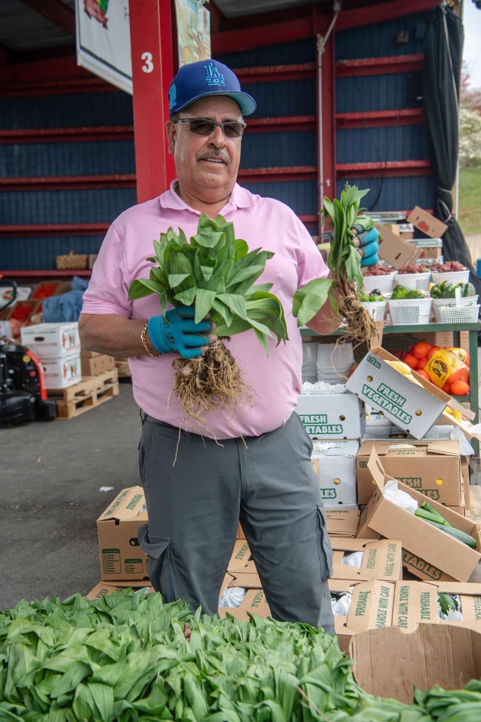 Efren Barraza holds bunches of ramps at his produce stand at the WNC Farmers Market, April 17, 2024.