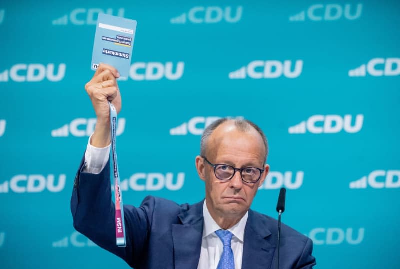 Friedrich Merz, Federal Chairman of the Christian Democratic Union (CDU), holds up his voting card as he speaks during the CDU Federal Party Conference. Michael Kappeler/dpa