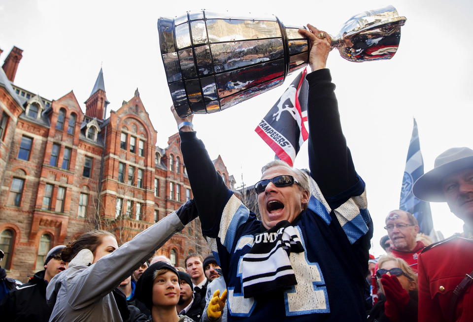 A CFL alumni hoists the Grey Cup above his head during the fan march before the Toronto Argonauts take on the Calgary Stampeders for the 100th Grey Cup in Toronto on Sunday, Nov. 25, 2012. THE CANADIAN PRESS/Michelle Siu