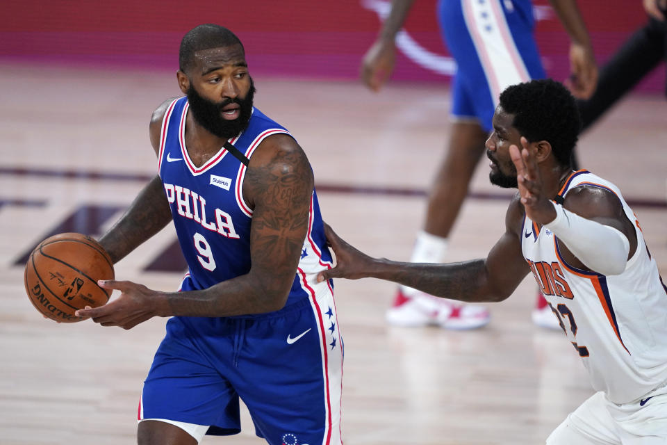 Philadelphia 76ers center Kyle O'Quinn (9) looks for help as Phoenix Suns center Deandre Ayton, right, defends during the first half of an NBA basketball game Tuesday, Aug. 11, 2020, in Lake Buena Vista, Fla. (AP Photo/Ashley Landis, Pool)