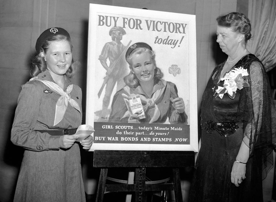 FILE - In this March 9, 1943 file photo, Eleanor Roosevelt, right, stands with Girl Scout Betty Bredin, from Kew Gardens, N.Y., who posed for the Girl Scout War Bond poster at center in New York. It's been 100 years since Juliette Gordon Low recruited the first scouts in Georgia. Low's original registration book from March of 1912 shows 102 recruits. Now there are 2.3 million active Girl Scouts nationwide. (AP Photo/Anthony Camerano, File)