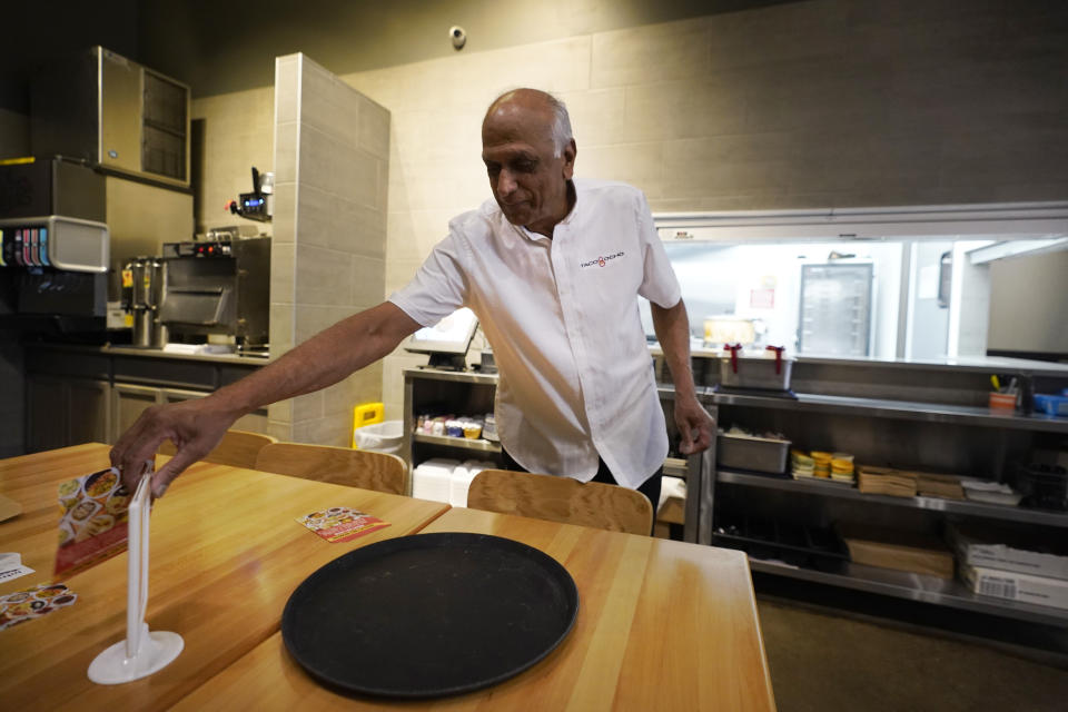 Mani Bhushan, owner of Taco Ocho, puts out table menus at one of his restaurants in McKinney, Texas, Friday, Nov. 11, 2022. Bhushan struggles to hire workers in the McKinney location, which opened in July 2021. He said many workers can't afford to live in this upscale suburb and have to travel from elsewhere. (AP Photo/LM Otero)