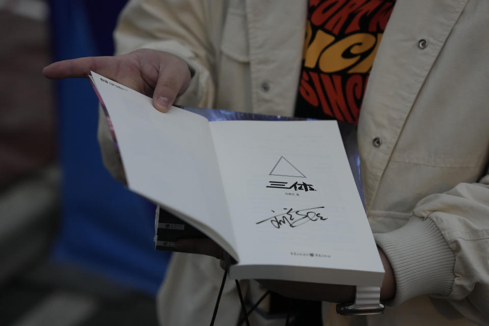 Tao Bolin, a 25-year-old influencer and science-fiction fan, holds a signed copy of "The Three-Body Problem" outside the World Science Fiction Convention in Chengdu, Sichuan province on Friday, Oct. 20, 2023. Tao grew up watching Japanese anime and always hoped his own country, China, would one day spawn science fiction stories enjoyed by the rest of the world. The series that began with "The Three-Body Problem," written by former engineer Liu Cixin, helped Chinese science fiction break through internationally, winning awards and making it onto the reading lists of the likes of former U.S. President Barack Obama and Mark Zuckerberg. (AP Photo/Ng Han Guan)