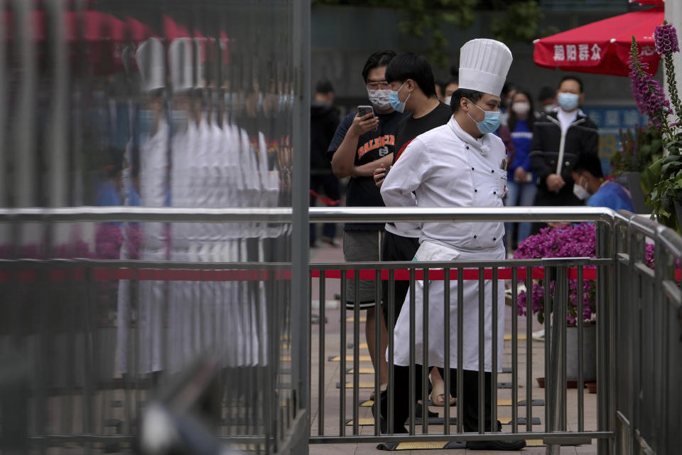A chef and lines up for public COVID-19 testing in the Chaoyang district on Wednesday, May 11, 2022, in Beijing. Shanghai reaffirmed China's strict "zero-COVID" approach to pandemic control Wednesday, a day after the head of the World Health Organization said that was not sustainable and urged China to change strategies. (AP Photo/Andy Wong)