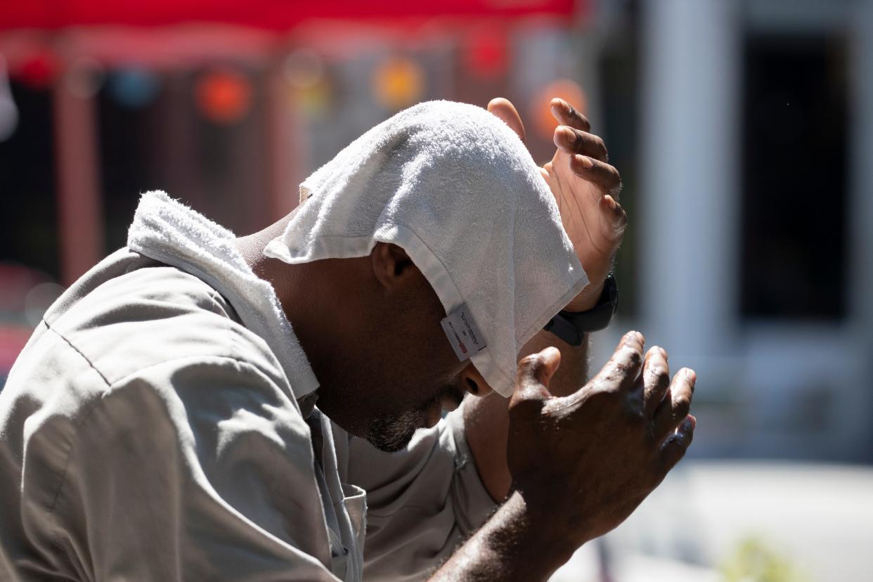 A man uses a wet towel to cool off, Tuesday, July 28, 2020, in New York. The city opened more than 300 fire hydrants with sprinkler caps to help residents cool off during a heat wave.