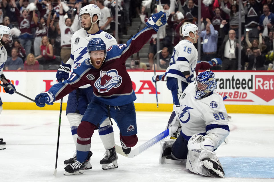 Colorado Avalanche left wing J.T. Compher, left, celebrates next to Tampa Bay Lightning goaltender Andrei Vasilevskiy, right, after an overtime goal by Andre Burakovsky in Game 1 of the NHL hockey Stanley Cup Final on Wednesday, June 15, 2022, in Denver. (AP Photo/John Locher )