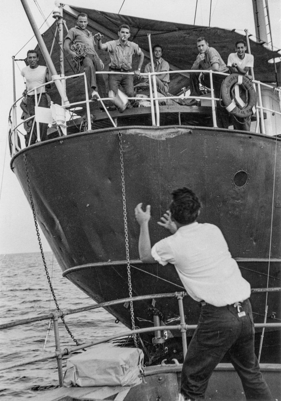 Local fishermen exchange goods with crew men on U.S. lightship Barnegat circa 1950.