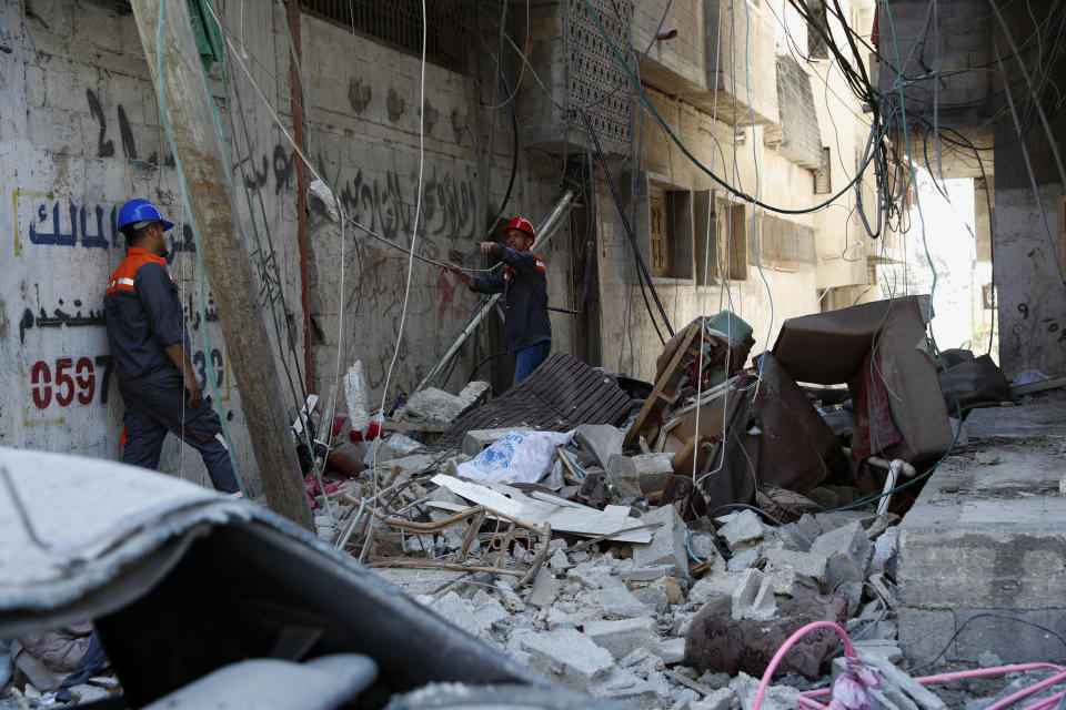 Workers inspect the rubble of the destroyed Abu Hussein building that was hit by an Israeli airstrike early morning, in Gaza City, Wednesday, May 19, 2021. (AP Photo/Adel Hana)