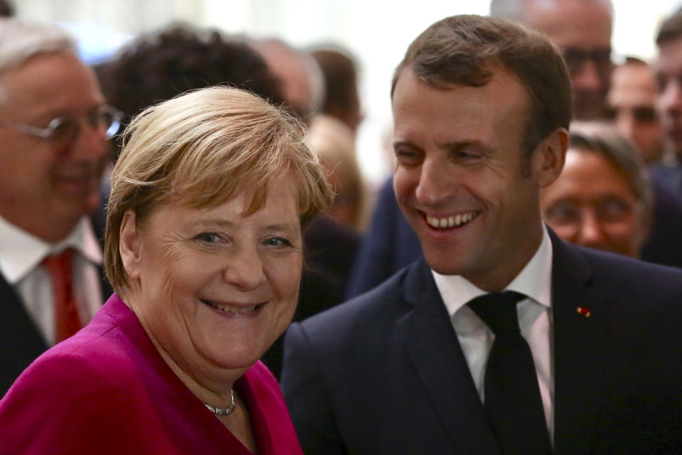 French President Emmanuel Macron shares a laugh with German Chancellor Angela Merkel as they visit the assembly line of the Airbus A350 in Toulouse, southwestern France, Wednesday, Oct.16, 2019. French President Emmanuel Macron and German Chancellor Angela Merkel are meeting in southern France, one day before a key EU summit that may approve a divorce deal with Britain. (AP Photo/Frederic Scheiber, Pool)