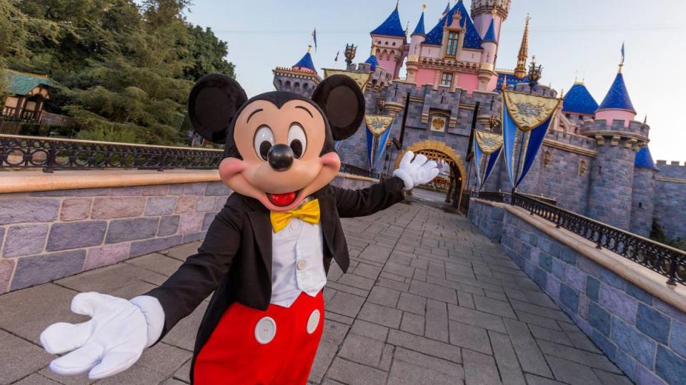 disney work from home: Mickey Mouse poses in front of Sleeping Beauty Castle at Disneyland Park