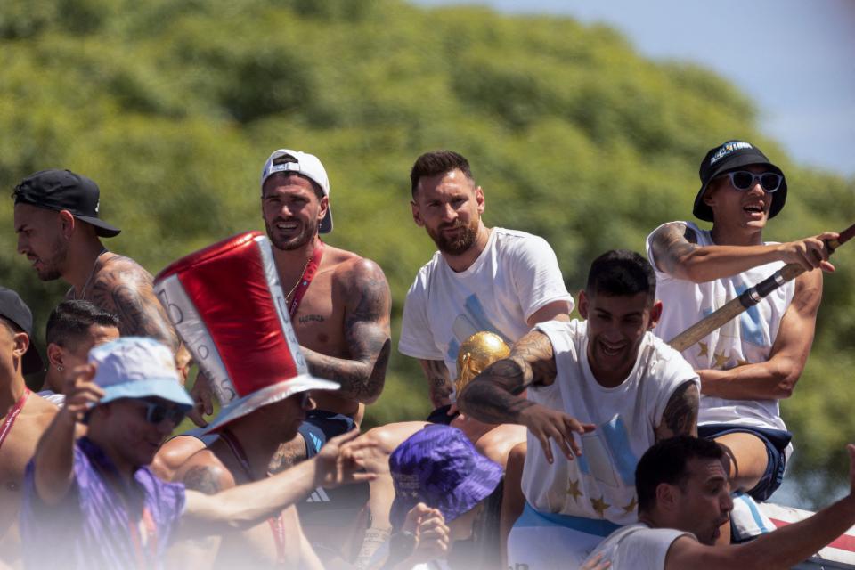 Argentine players Rodrigo De Paul (L) and Lionel Messi (R) celebrate on board a bus with a sign reading 