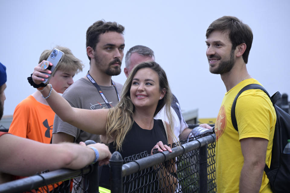 Daniel Suarez, right, poses for photos with fans before a NASCAR Cup Series auto race at Daytona International Speedway, Friday, Aug. 26, 2022, in Daytona Beach, Fla. (AP Photo/Phelan M. Ebenhack)