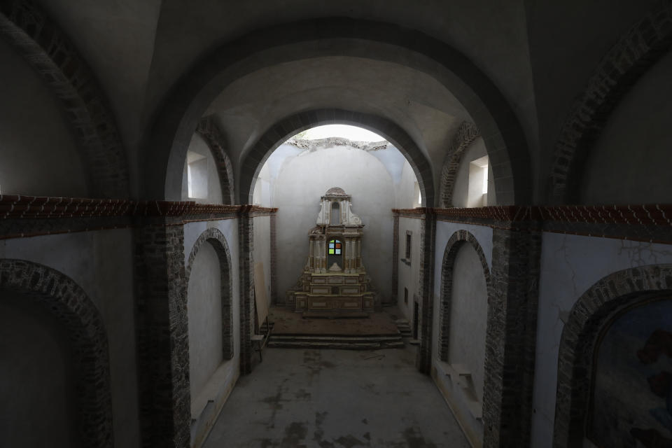 The damaged altar stands below a collapsed section of the vault, now shielded by a temporary metal roof, at the former San Guillermo Convent, where restoration work is underway three years after an earthquake damaged its church and adjacent cloisters, in Totolapan, Morelos state, Mexico, Tuesday, Oct. 13, 2020. Experts restoring buildings and monuments here have faced every kind of challenge: how to replace a bent old steel support completely encapsulated inside a slender stone column hundreds of feet tall; how to fix foundations sunk in swampy soil; how to restore church bell towers that are central to village life. (AP Photo/Rebecca Blackwell)