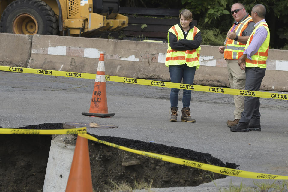 From left, Gov. Maura Healey speaks with MBTA Chief Railroad Officer Ryan Conolan andMBTA General Manager and CEO Phillip Eng beside a sink hole and a washed out the embankment below a Commuter Rail train line, Tuesday, Sept. 12, 2023, in Leominster, Mass. More than 9 inches of rain fell in the town overnight. (AP Photo/Josh Reynolds)