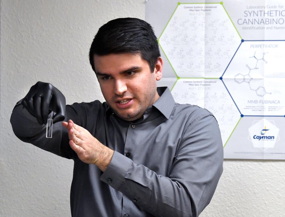 Christopher Cisneros, a forensic scientist at the Texas Department of Public Safety Crime Lab, holds a quartz cuvette, demonstrating to visitors Friday how light passes through it to analyze the chemical composition of drugs seized by troopers.