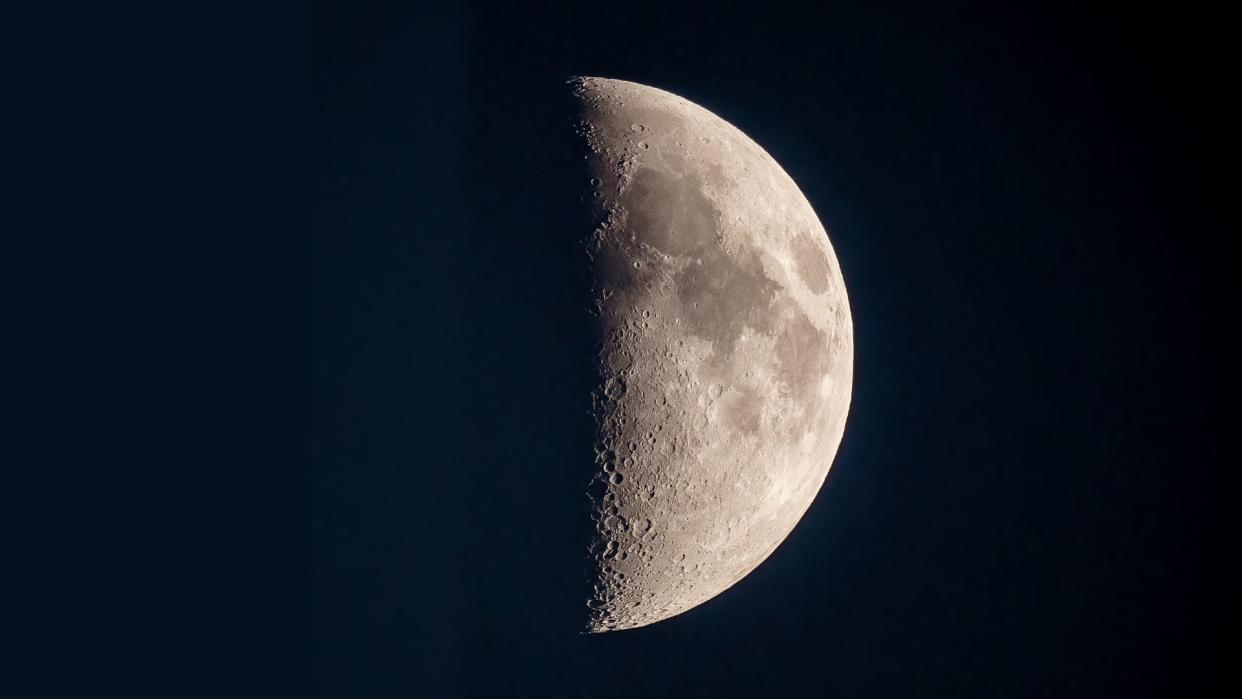  A half-lit moon in a dark sky. 