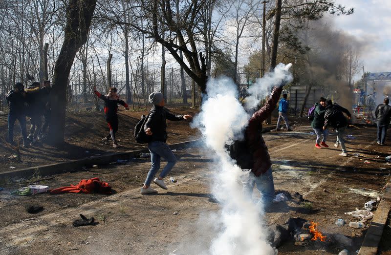 Migrants throw back tear gas canisters during clashes with Greek police, at the Turkey's Pazarkule border crossing with Greece's Kastanies, in Edirne