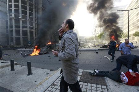 People run to help a wounded man as smoke rises from the site of an explosion in Beirut's downtown area