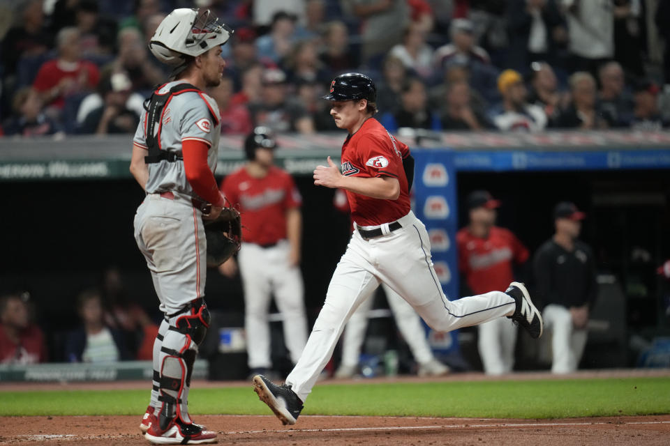 Cleveland Guardians' Kyle Manzardo, right, runs home past Cincinnati Reds catcher Tyler Stephenson, left, to score on a sacrifice fly hit by Josh Naylor in the seventh inning of a baseball game in Cleveland, Tuesday, Sept. 24, 2024. (AP Photo/Sue Ogrocki)