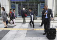 In this Oct. 10, 2018, photo, people walk by an electronic stock board of a securities firm in Tokyo. Asian stock markets sank Friday, Oct. 19, 2018, after Wall Street declined on losses for tech and industrial stocks and Chinese economic growth slowed. (AP Photo/Koji Sasahara)