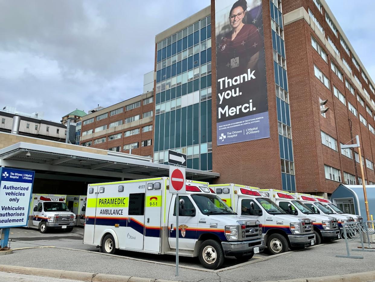 Ottawa Paramedic Service ambulances sit outside the emergency department of the Civic campus of The Ottawa Hospital. A pilot program to transport some patients to hospital by taxi is facing delays. (Kate Porter/CBC - image credit)