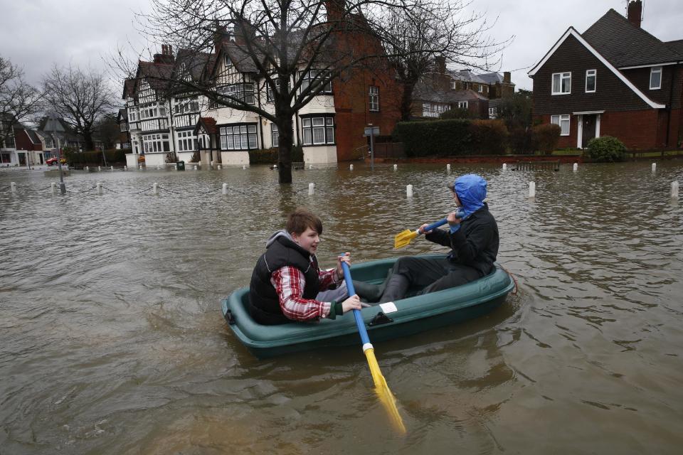 Children paddle their inflatable boat through a flooded street, in the centre of the village of Datchet, England, Tuesday, Feb. 11, 2014. The River Thames has burst its banks after reaching its highest level in years, flooding riverside towns upstream of London. Residents and British troops piled up sandbags to protect properties from the latest bout of flooding, but the river overwhelmed their defenses in several places Monday, leaving areas including the center of the village of Datchet underwater. (AP Photo/Lefteris Pitarakis)