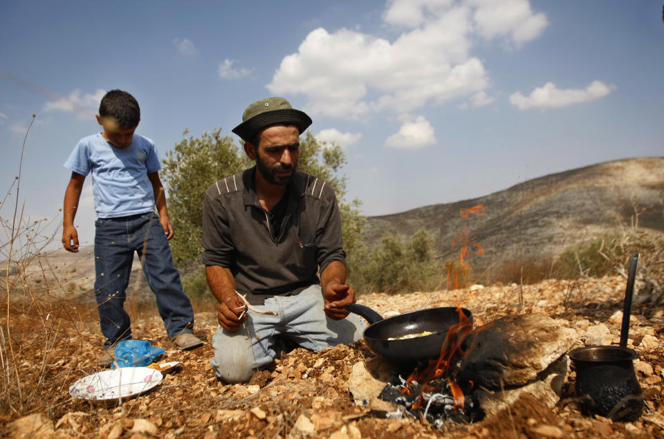 In this photograph made on Monday, Oct. 22, 2012, a Palestinian farmer Khader Khader, 31, cooks food on his land in Nisf Jubeil, near the West Bank city of Nablus. In an emerging back-to-the-land movement, Palestinian farmers are turning the rocky hills of the West Bank into organic olive groves, selling their oil to high-end grocers in the U.S. and Europe. (AP Photo/Majdi Mohammed).
