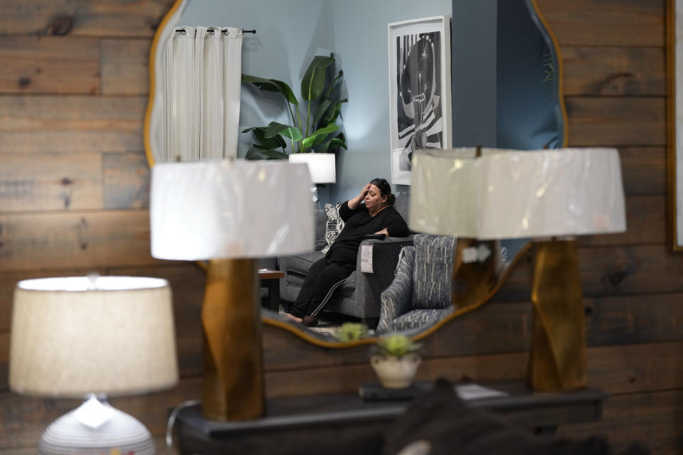 Houston resident Adriana Guerrero is reflected in a mirror as she spend time at Gallery Furniture, which is being used as a temporary shelter, to cool off and and have a meal, Tuesday, July 9, 2024, in Houston. The effects of Hurricane Beryl left most in the area without power. (AP Photo/Eric Gay)