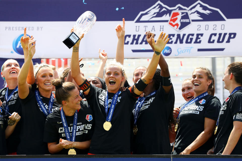 Rachel Daly holds up the NWSL Challenge Cup trophy with her teammates.