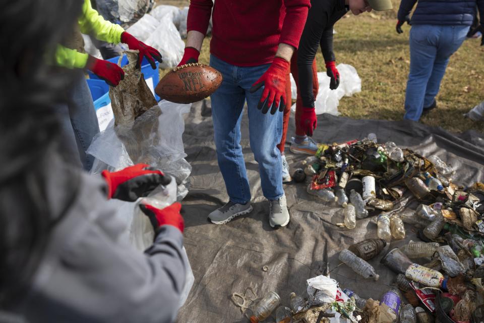 A volunteer holds a discarded football following a trash collection on Wednesday, Nov. 15, 2023, at Anacostia Park in Washington. For decades, the Anacostia was treated as a municipal dumping ground for industrial waste, storm sewers and trash. A sewer upgrade in the city and decades of local environmental advocacy have brought improvements to the river, but change has come slowly. (AP Photo/Tom Brenner)